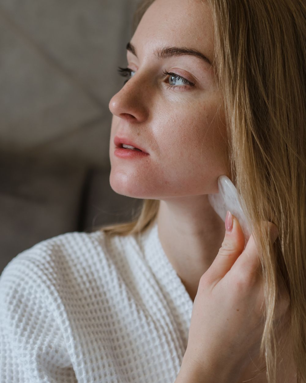 Mujer masajeando su rostro con una gua sha de cuarzo