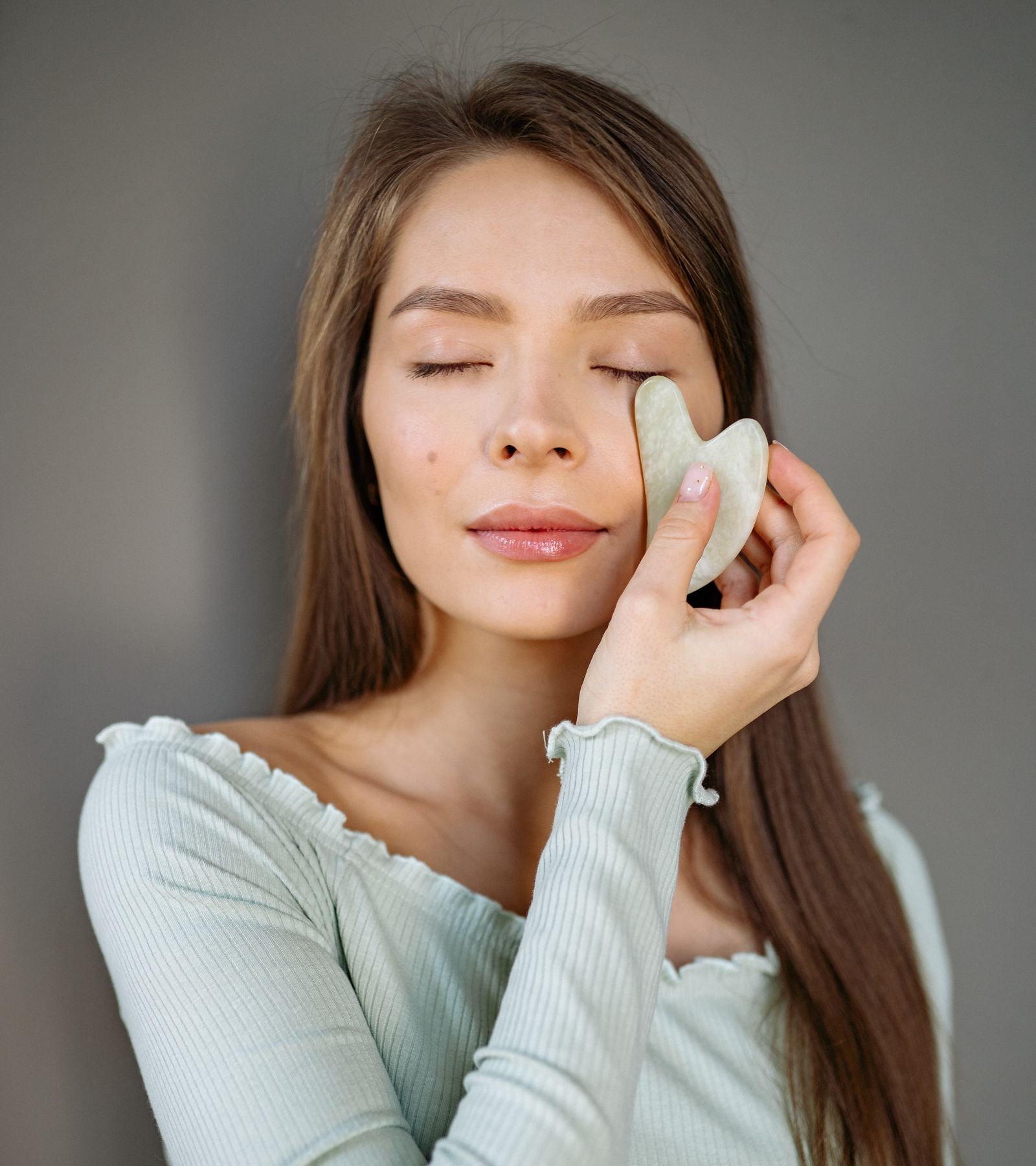 Mujer con los ojos cerrados usando un masajeador facial